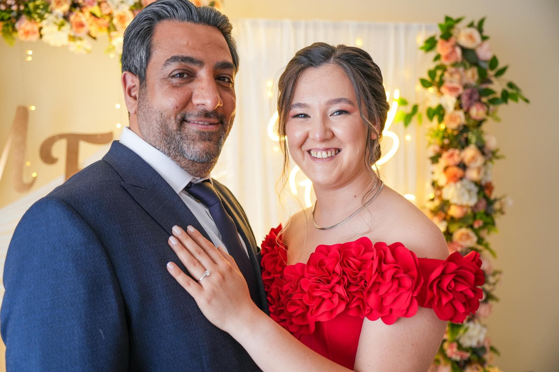 Engaged couple with floral arch and warm reception lighting