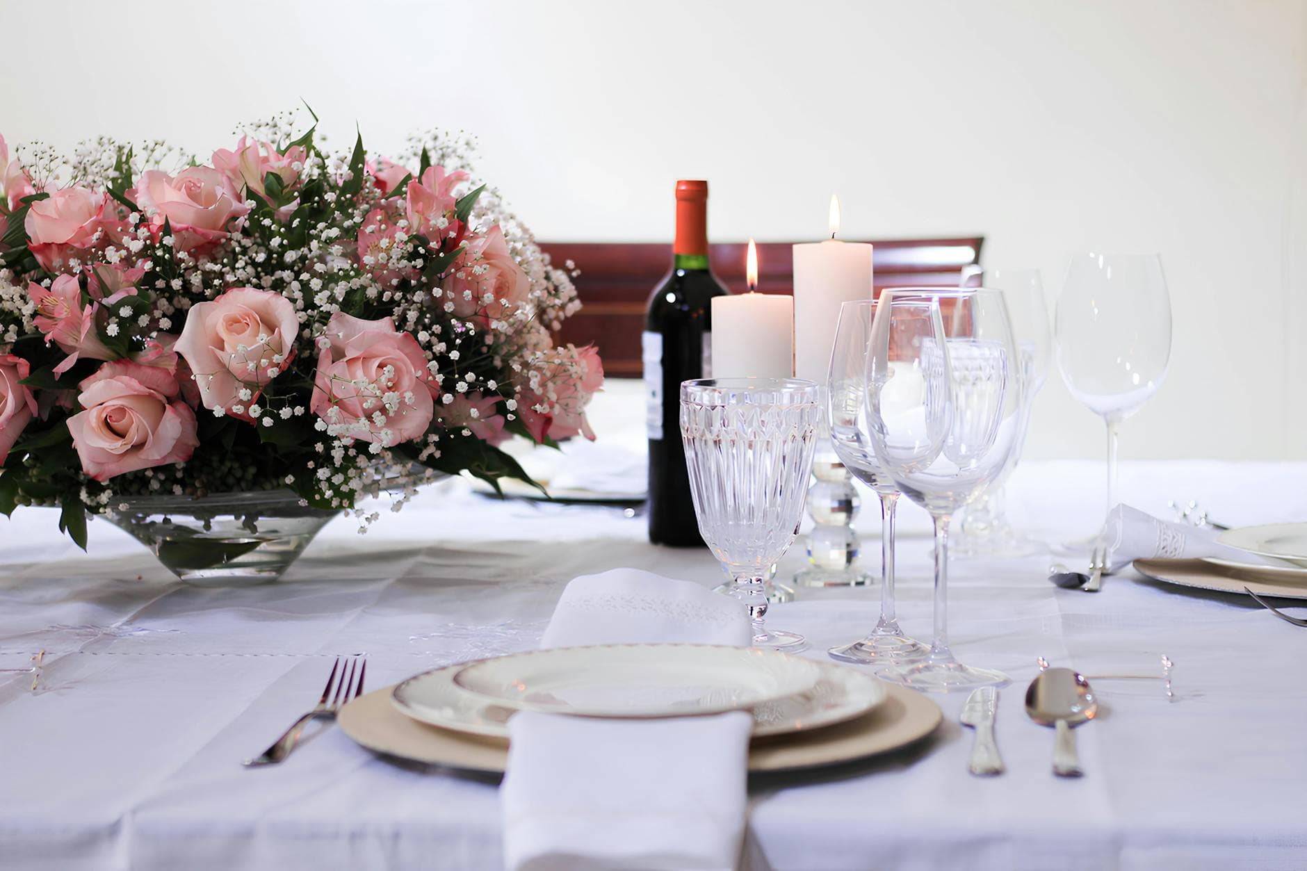 Romantic dinner table with pink roses, candles, and crystal glassware