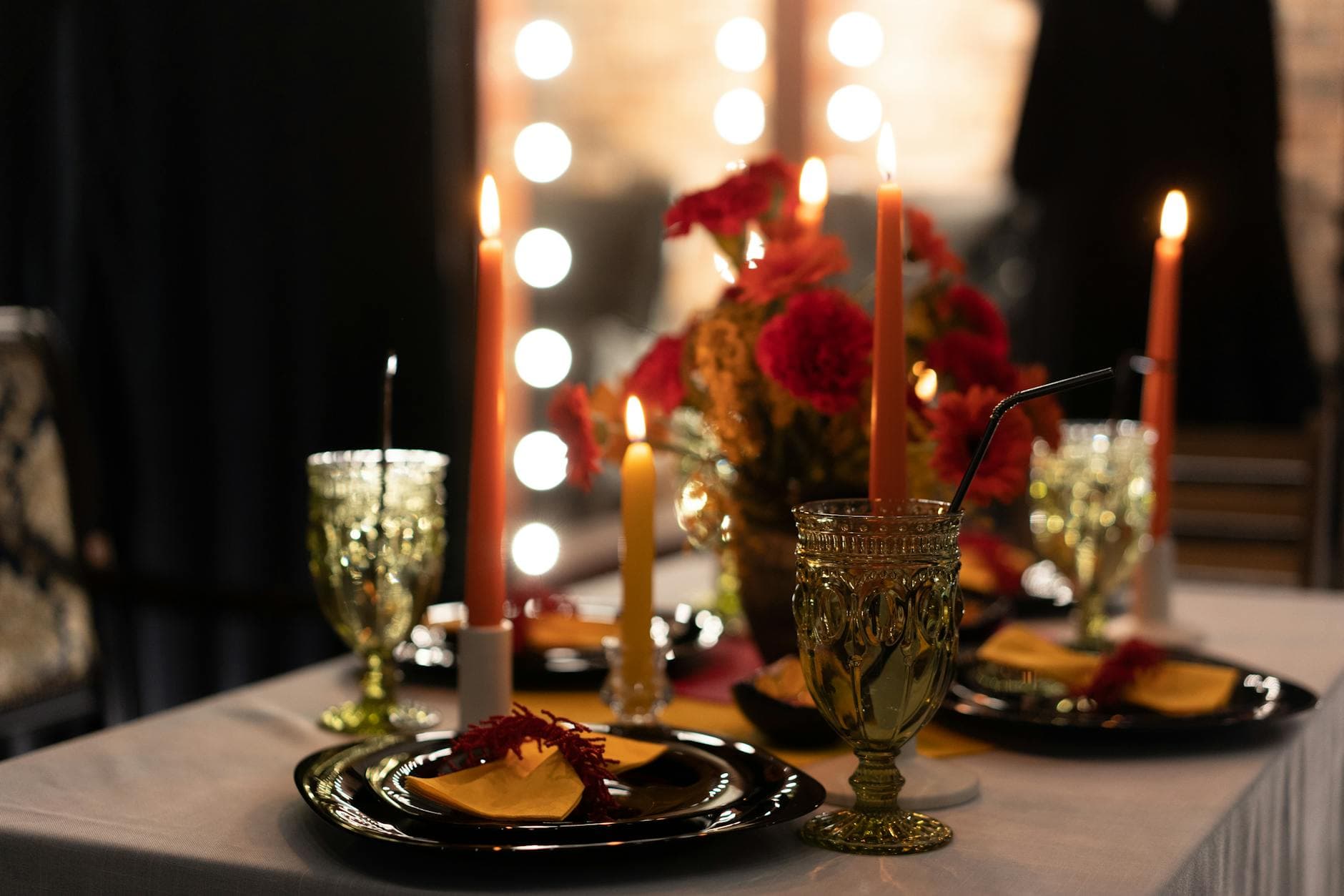 Intimate candlelit table setting with red florals and goblets